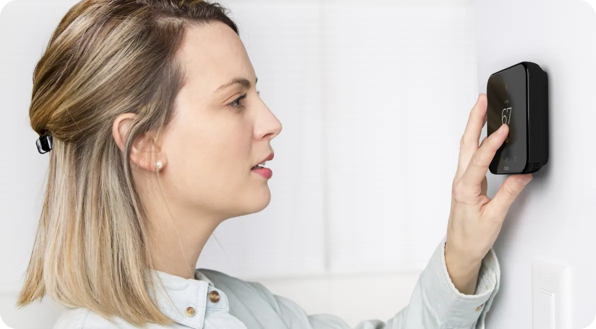Woman using cielo smart thermostat on wall