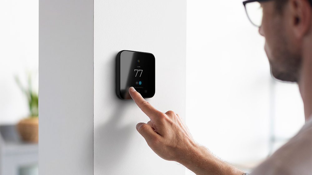 man changing temperature settings on smart thermostat 