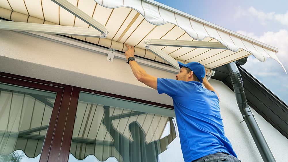 A man installing an awning to keep cool without AC