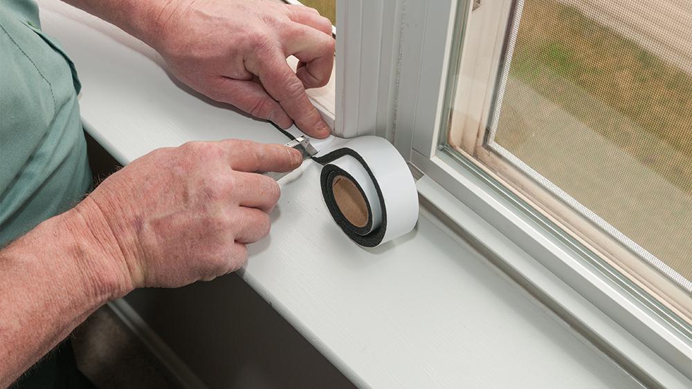 A man applying weatherstripping on the windows