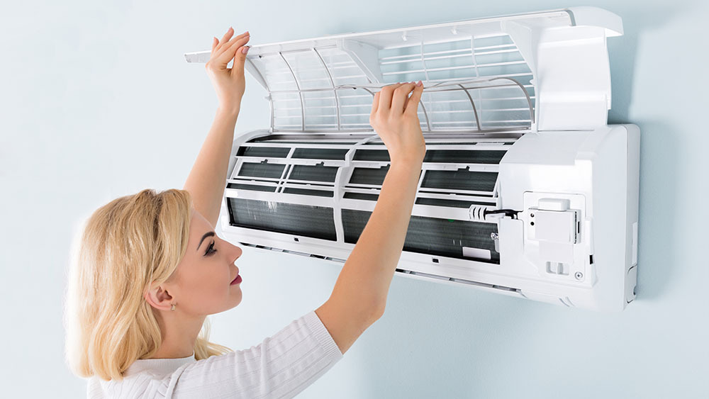 HVAC technician cleaning mini-split to prevent AC drain line from getting clogged