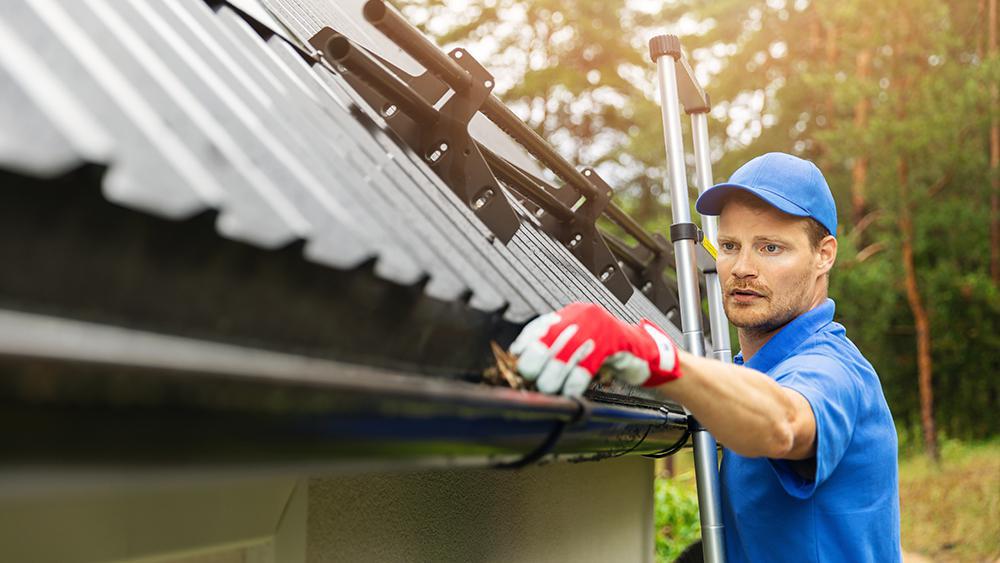 A man cleaning gutters before the onset of winter season