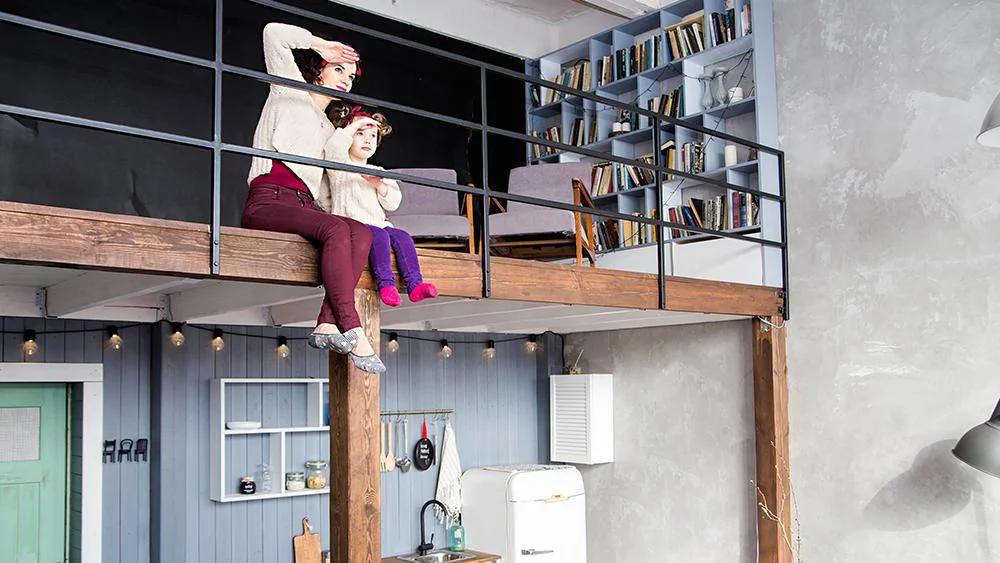 Two girls sitting upstairs in a 2 story house