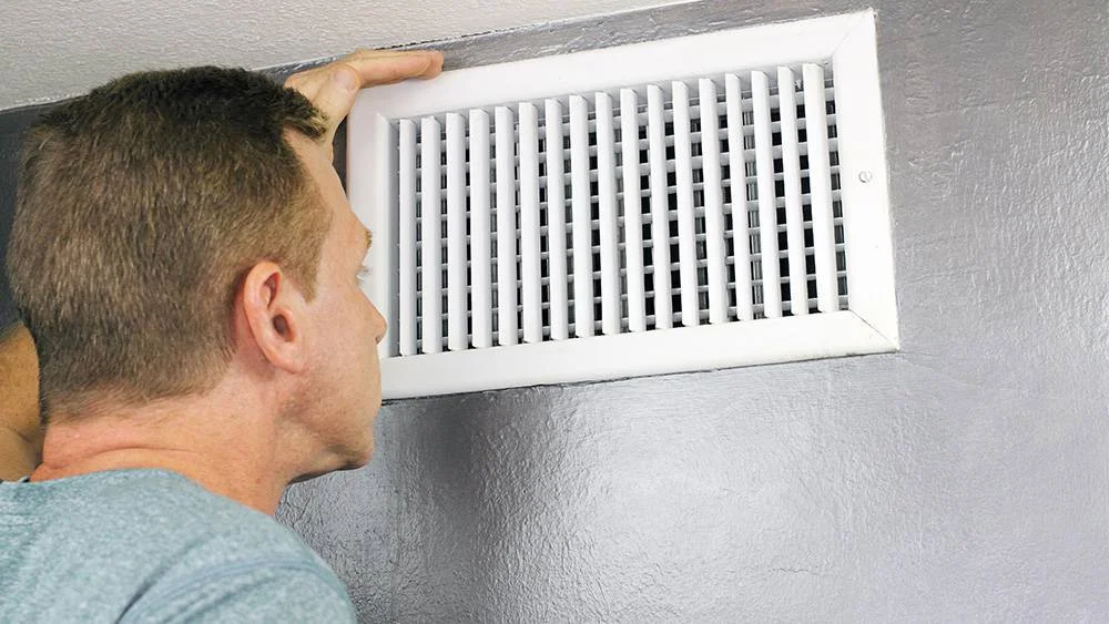 man checking air vents