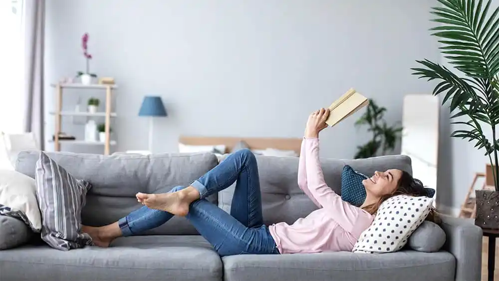 Girl reading a book on the couch.