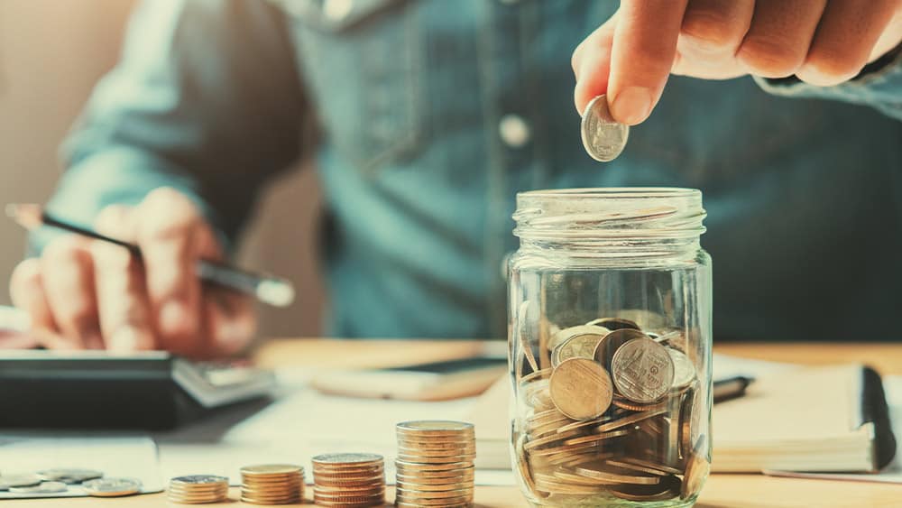 Man putting a coin in a jar.