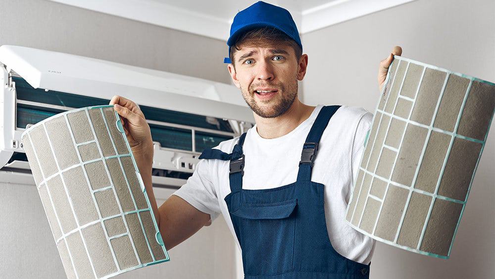 HVAC professional holding air conditioner filter.
