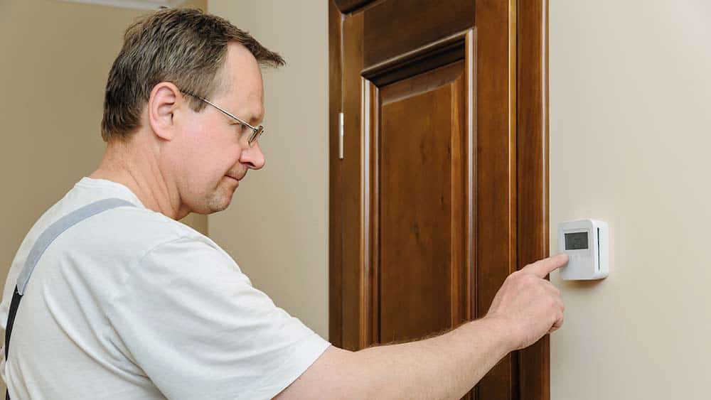 Man changing thermostat setting.