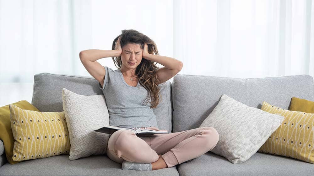 Woman annoyed due to air conditioner noise.