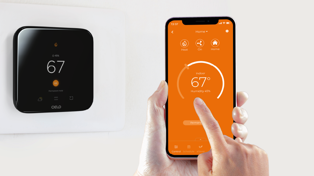 A person using Cielo Home app. Cielo smart thermostat is installed on the side.