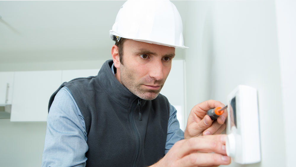 HVAC technician fixing a thermostat